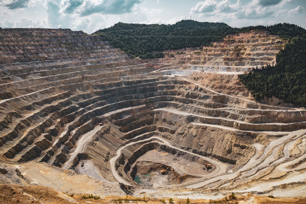 Aerial view of a large open-pit mine with terraced excavation during summer.